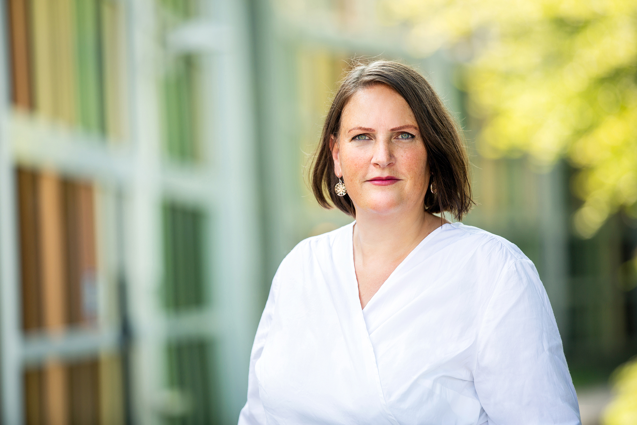 Potrait von Julia , sie hat braune kinnlange Haare, trägt eine weiße Bluse und weinroten Lippenstift