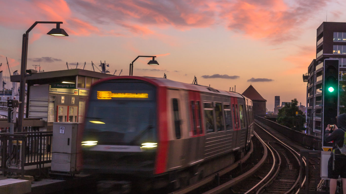 Hochbahn U-Bahn fährt aus Station, Hintergrund rosa Himmel vom Sonnuntergang