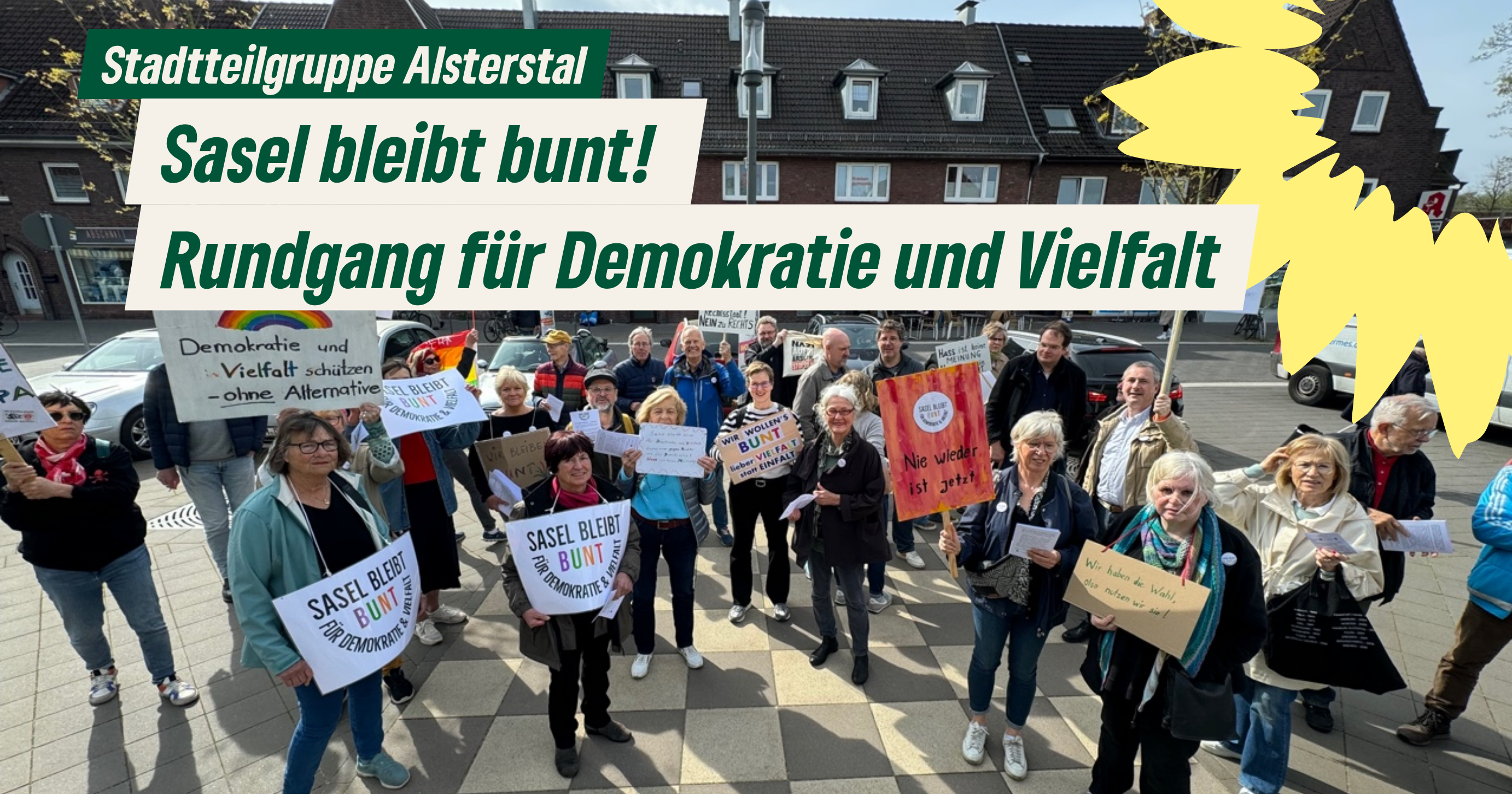 Eine Gruppe von Menschen mit Plakaten zum Thema Demokratie und Vielfalt hat sich versammelt