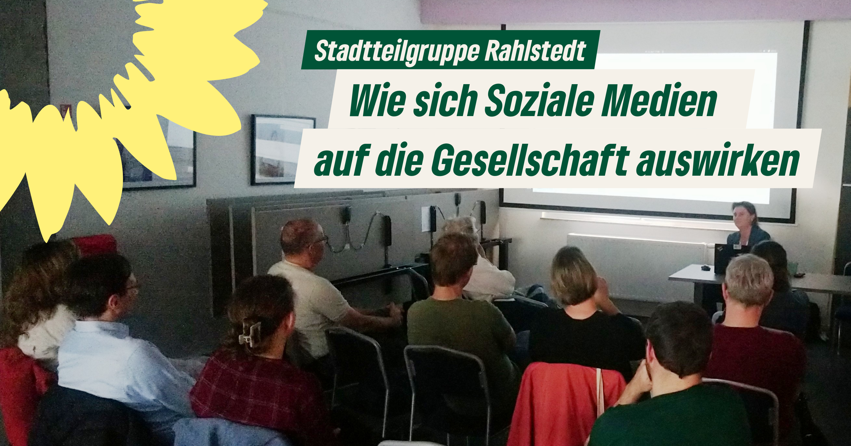 Eine Gruppe von Personen sitzt in einem Raum und folgt einer Präsentation